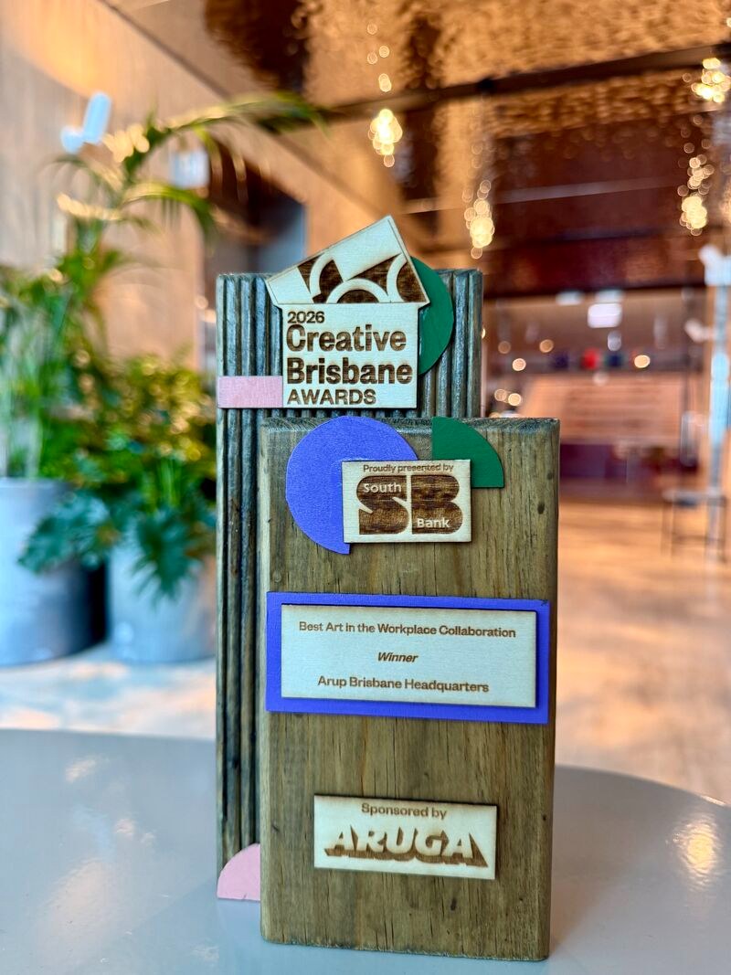 A 2026 Creative Brisbane Award in reclaimed timber with layered painted shapes, engraved 'Best Art in the Workplace Collaboration — Arup Brisbane Headquarters'.