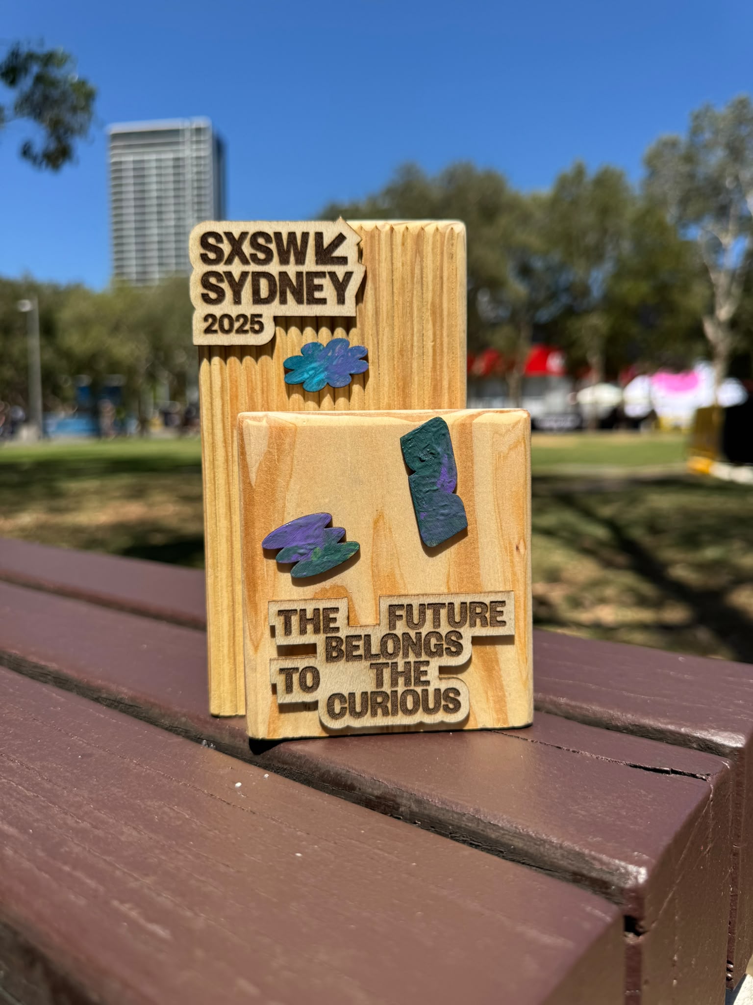 A reclaimed-timber SXSW Sydney 2025 conference piece, engraved "the future belongs to the curious".