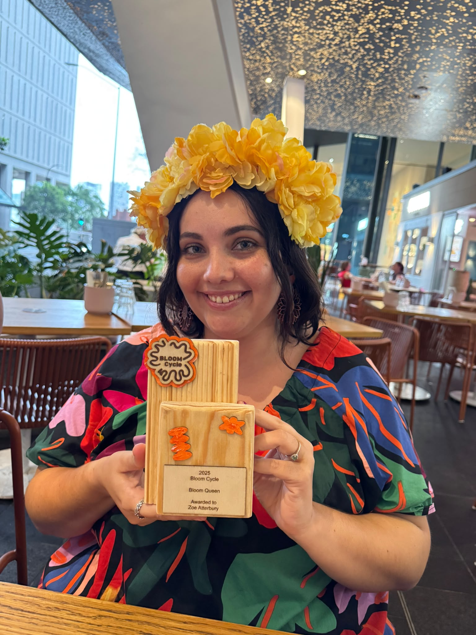 Zoe Atterbury holding a Bloom Cycle "Bloom Queen" staff award.