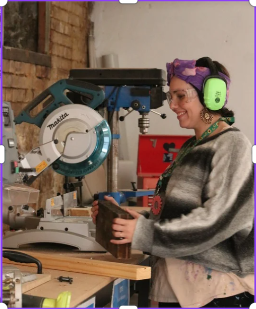 Zoe in the Bloom Cycle workshop using a drill press to craft a trophy from reclaimed timber.