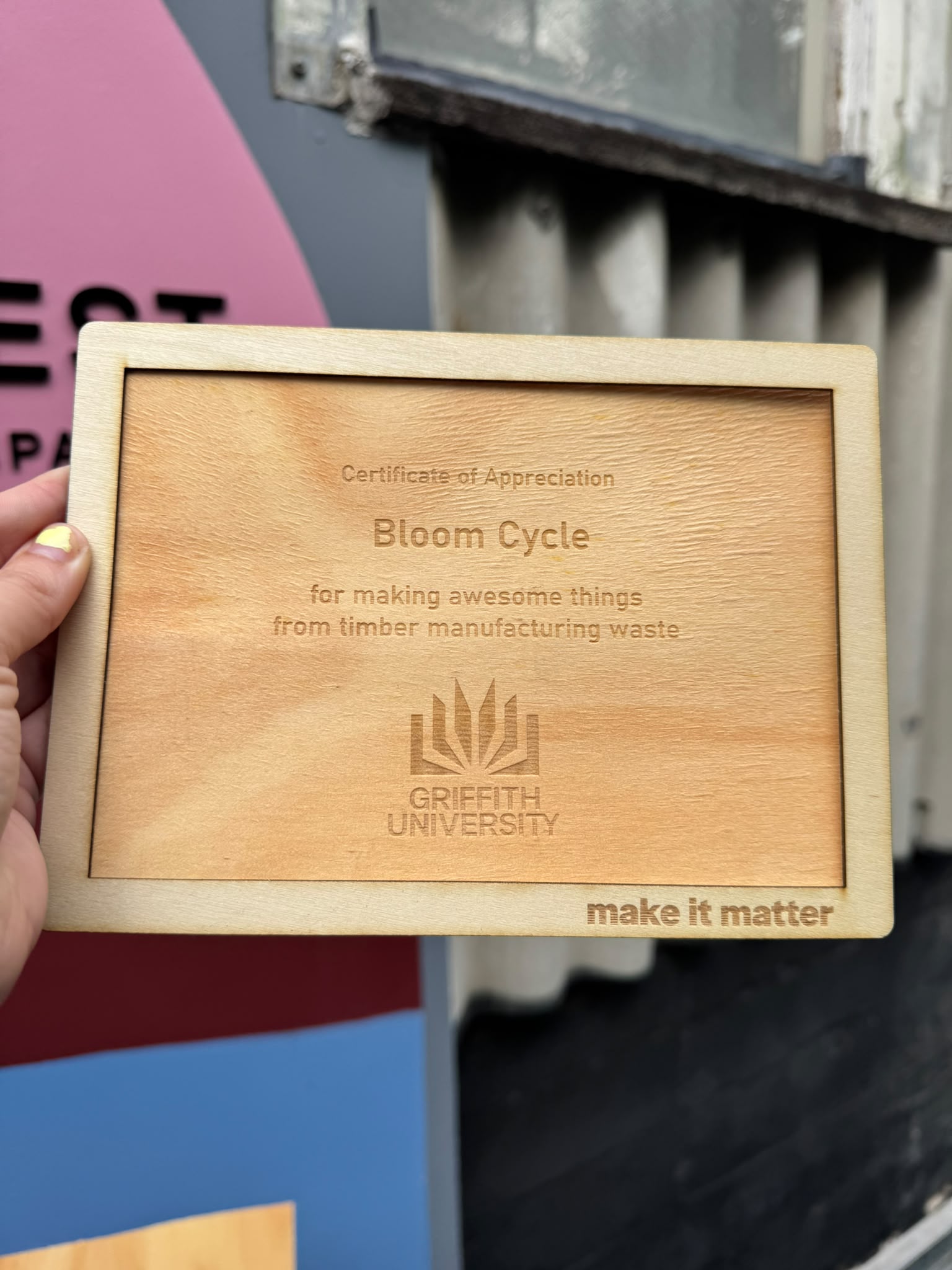 A framed reclaimed-timber certificate of appreciation engraved for Griffith University, reading 'for making awesome things from timber manufacturing waste'.