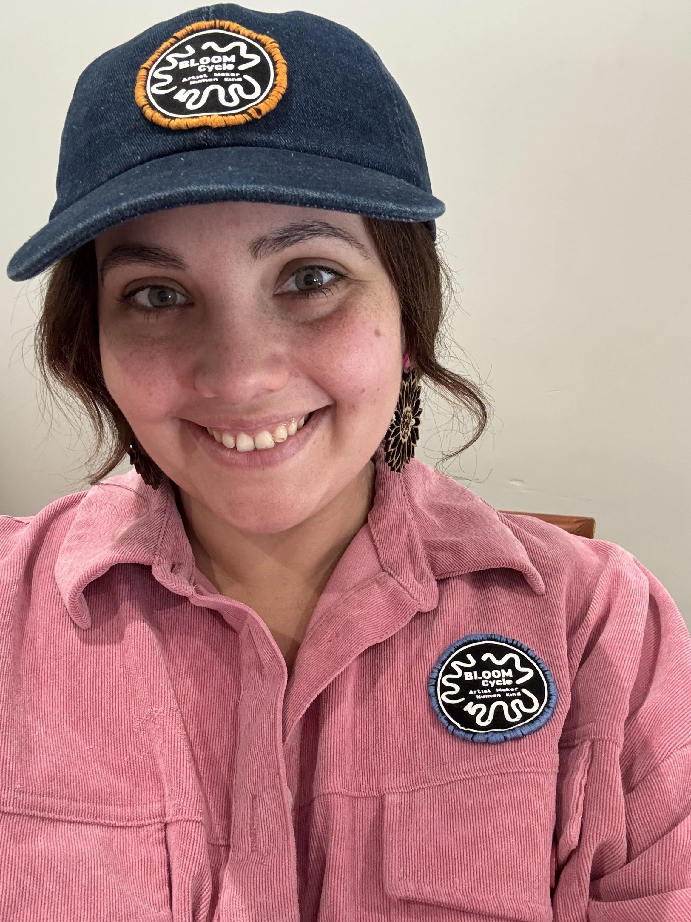 Zoe Atterbury, founder of Bloom Cycle, wearing a Bloom Cycle cap and pink corduroy shirt with the Bloom Cycle patch.